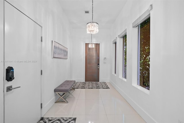 entrance foyer with plenty of natural light, light tile patterned flooring, and an inviting chandelier