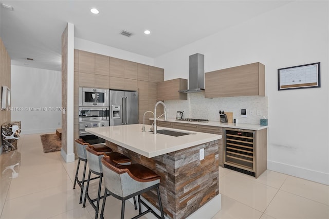 kitchen featuring wall chimney range hood, decorative backsplash, beverage cooler, sink, and stainless steel appliances