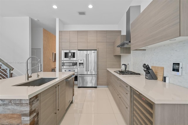 kitchen featuring wall chimney exhaust hood, tasteful backsplash, beverage cooler, appliances with stainless steel finishes, and sink