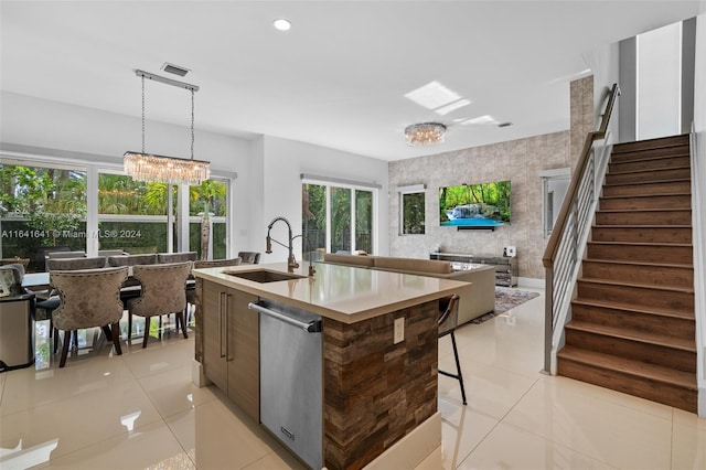 kitchen with sink, an inviting chandelier, an island with sink, light tile patterned floors, and hanging light fixtures