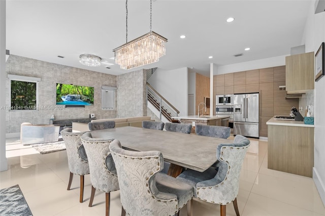 tiled dining space featuring tile walls, an inviting chandelier, and sink