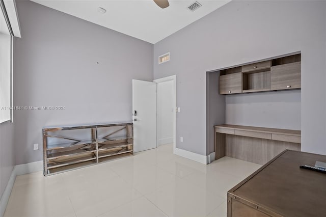 office space featuring a high ceiling, ceiling fan, and light tile patterned floors