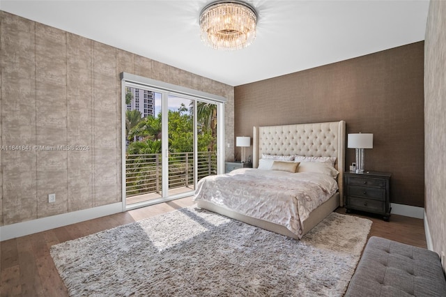 bedroom featuring hardwood / wood-style flooring, a chandelier, and access to outside