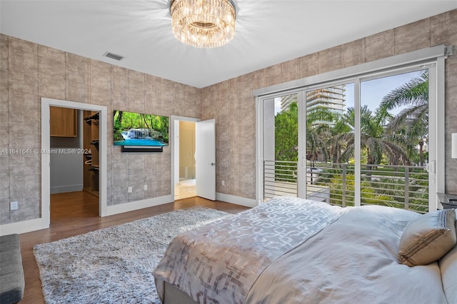 bedroom featuring hardwood / wood-style flooring, a notable chandelier, access to outside, and a walk in closet