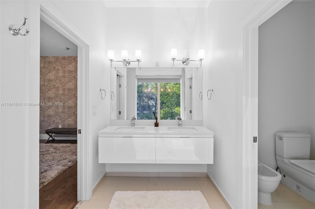 bathroom featuring toilet, a bidet, double sink vanity, and tile patterned floors