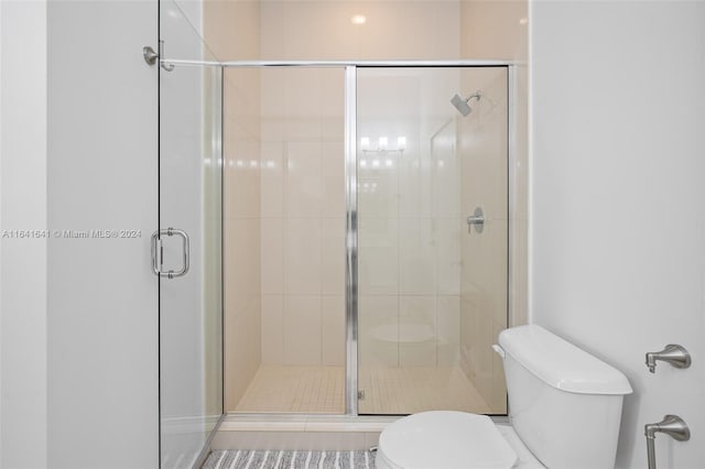 bathroom featuring an enclosed shower, toilet, and tile patterned floors