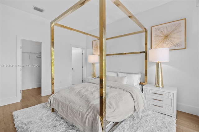 bedroom with a spacious closet, light hardwood / wood-style flooring, and a closet