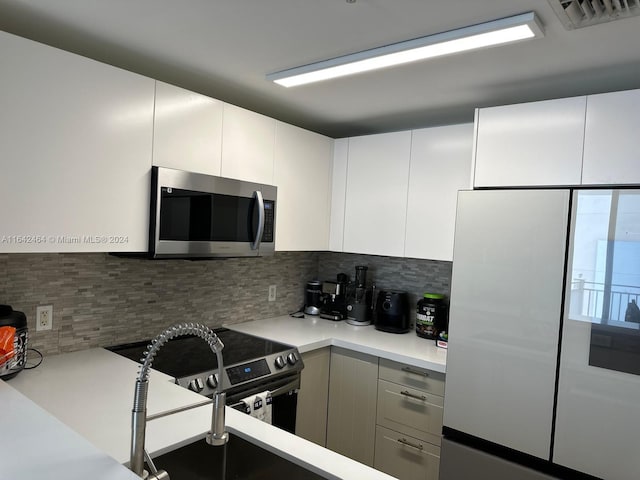 kitchen featuring visible vents, stainless steel appliances, light countertops, white cabinetry, and backsplash