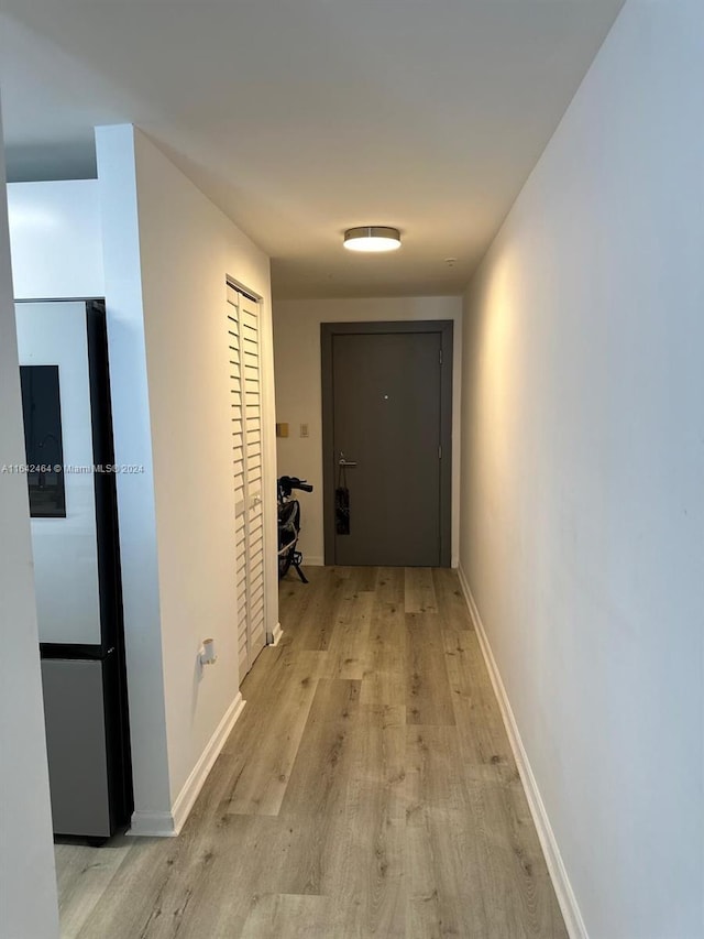 hallway featuring light wood finished floors and baseboards