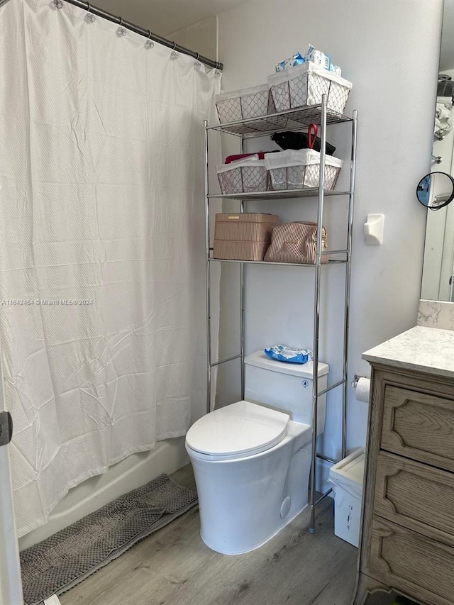 full bathroom with vanity, shower / bath combo with shower curtain, wood finished floors, and toilet