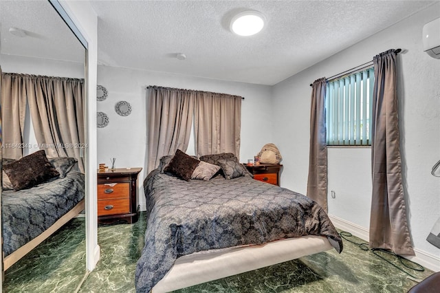 bedroom with a textured ceiling and a wall mounted air conditioner