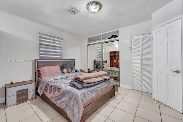 bedroom featuring multiple closets, a textured ceiling, and light tile patterned floors