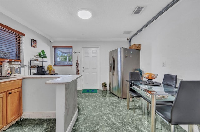 kitchen featuring a textured ceiling, stainless steel refrigerator with ice dispenser, and crown molding