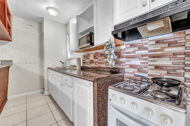 kitchen with white range oven, backsplash, light tile patterned floors, and white cabinets