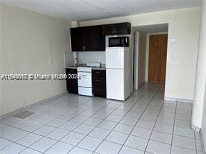 6484 Indian Creek Dr Unit 138, Miami Beach, FL 33141 - kitchen featuring freestanding refrigerator, stove, dark cabinetry, black microwave, and light tile patterned floors