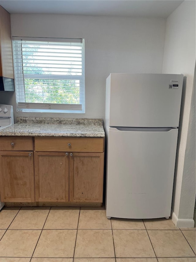 kitchen featuring light tile patterned flooring and white appliances