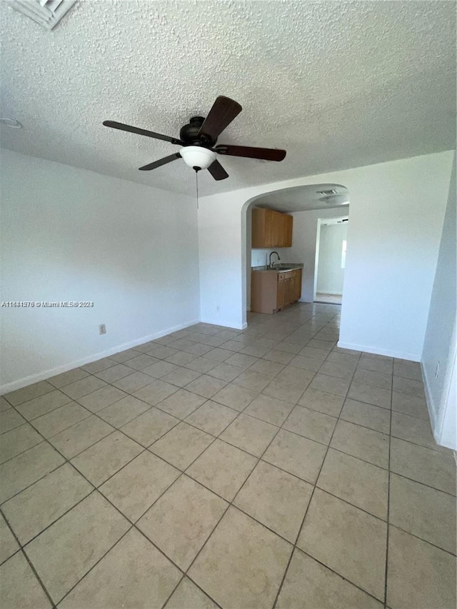 unfurnished bedroom featuring a textured ceiling, ceiling fan, light tile patterned floors, and sink