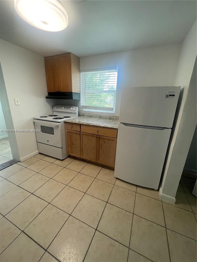 kitchen with light stone counters, white appliances, and light tile patterned floors