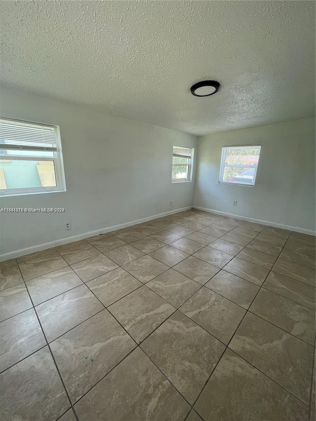 tiled empty room with a textured ceiling