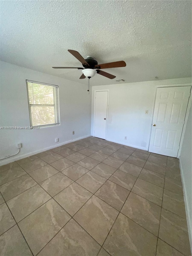 unfurnished bedroom with a textured ceiling, ceiling fan, and tile patterned floors