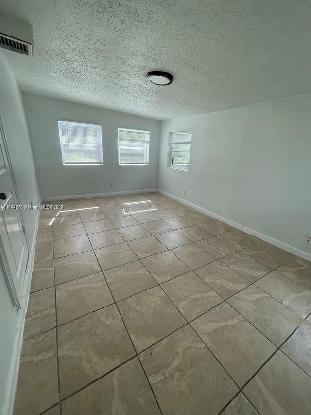 tiled spare room featuring a textured ceiling