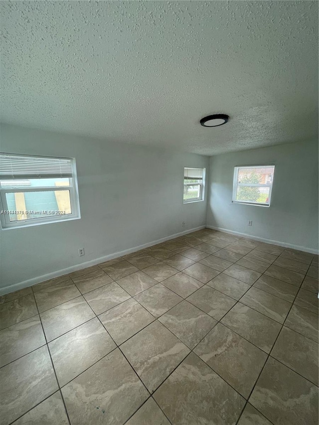 tiled spare room featuring a textured ceiling