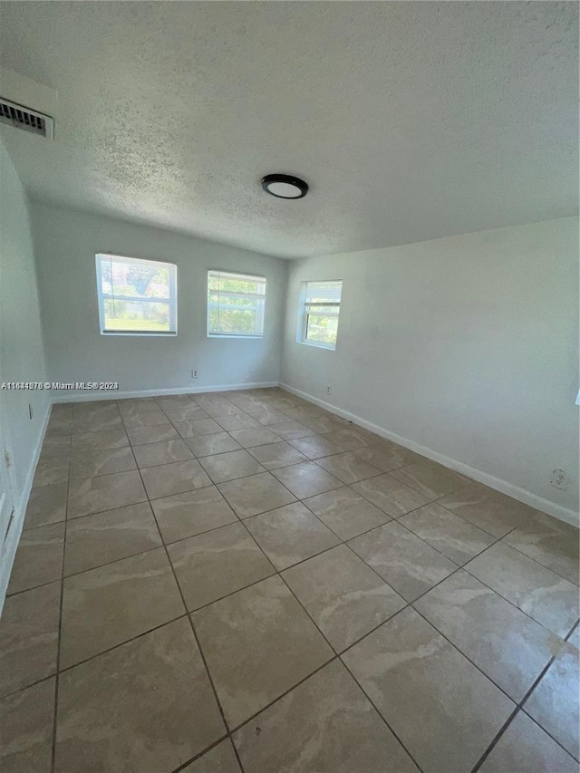 unfurnished room with a textured ceiling and light tile patterned flooring