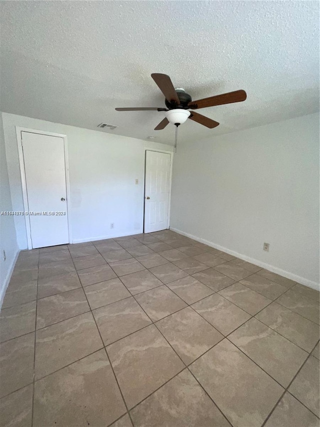 spare room with ceiling fan, a textured ceiling, and tile patterned floors