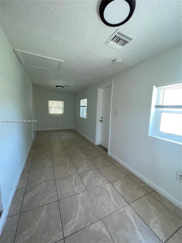 tiled spare room featuring a textured ceiling