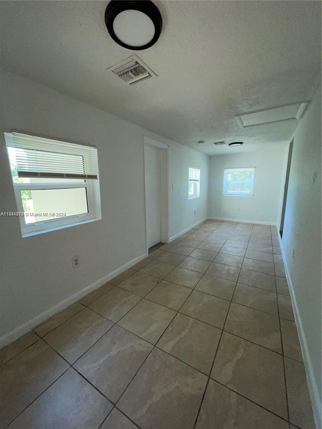 spare room featuring a textured ceiling and light tile patterned floors