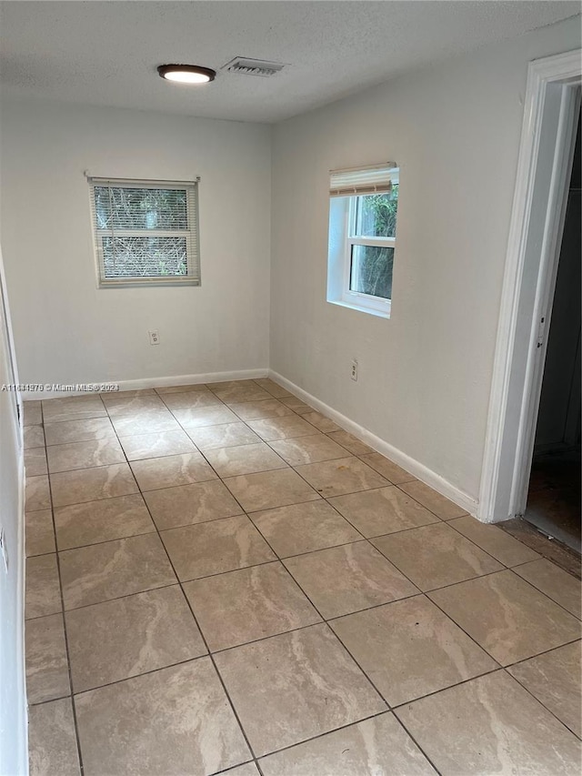 tiled spare room with a textured ceiling