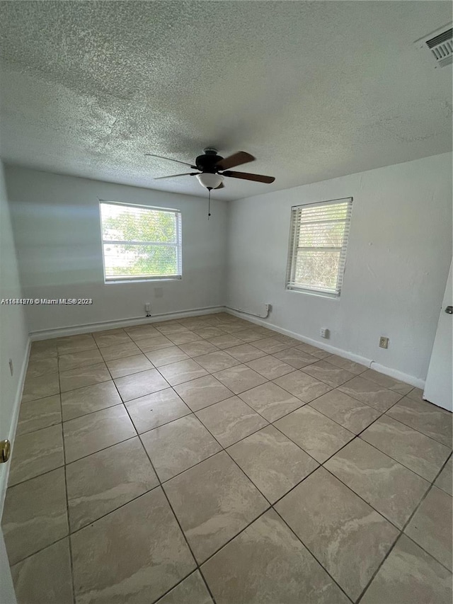 tiled empty room featuring ceiling fan and a textured ceiling