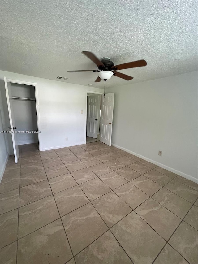 unfurnished bedroom featuring tile patterned flooring, a closet, ceiling fan, and a textured ceiling