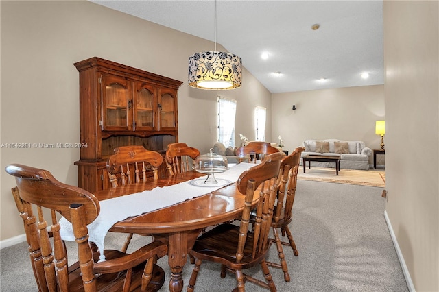 carpeted dining space featuring vaulted ceiling