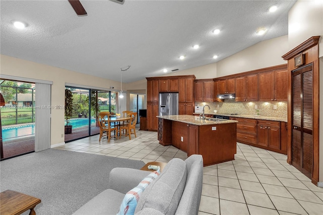 kitchen featuring a kitchen island with sink, hanging light fixtures, stainless steel refrigerator with ice dispenser, vaulted ceiling, and light tile patterned floors