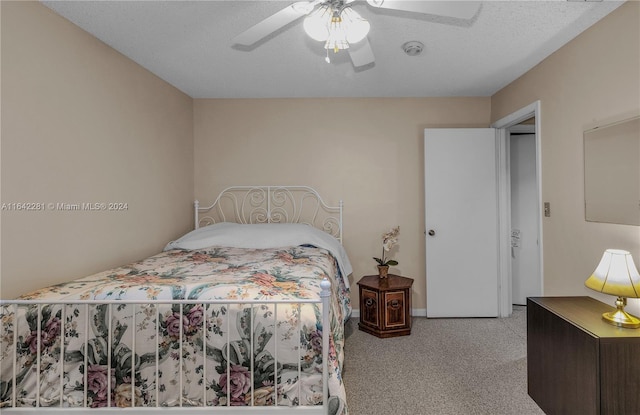 bedroom featuring ceiling fan, light carpet, and a textured ceiling