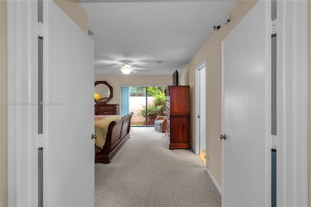 hall featuring a textured ceiling and light colored carpet