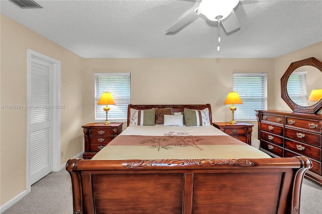 bedroom featuring ceiling fan, light colored carpet, and a textured ceiling