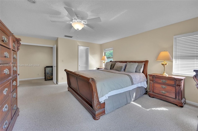 bedroom featuring light carpet, a textured ceiling, and ceiling fan