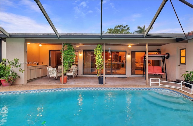 pool at dusk with a lanai and a patio area