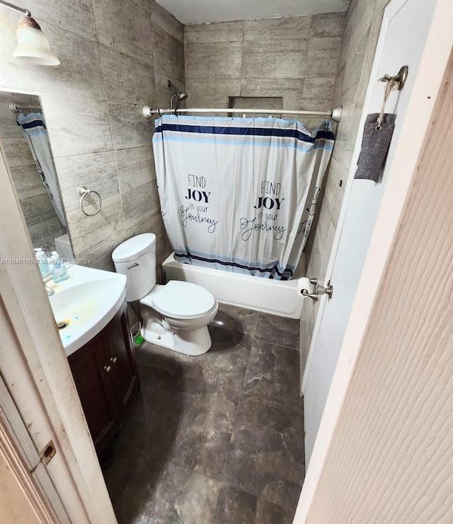 full bathroom featuring toilet, tile patterned flooring, shower / bath combo with shower curtain, vanity, and tile walls