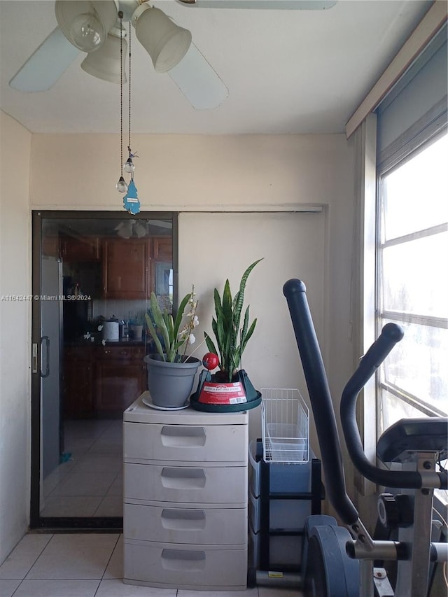 workout area with ceiling fan and light tile patterned floors