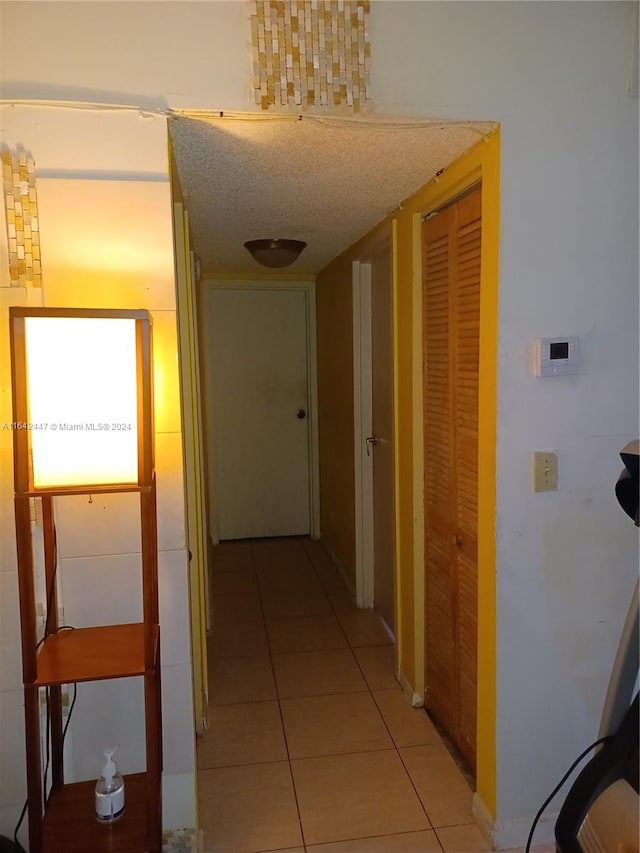 corridor with a textured ceiling and light tile patterned floors