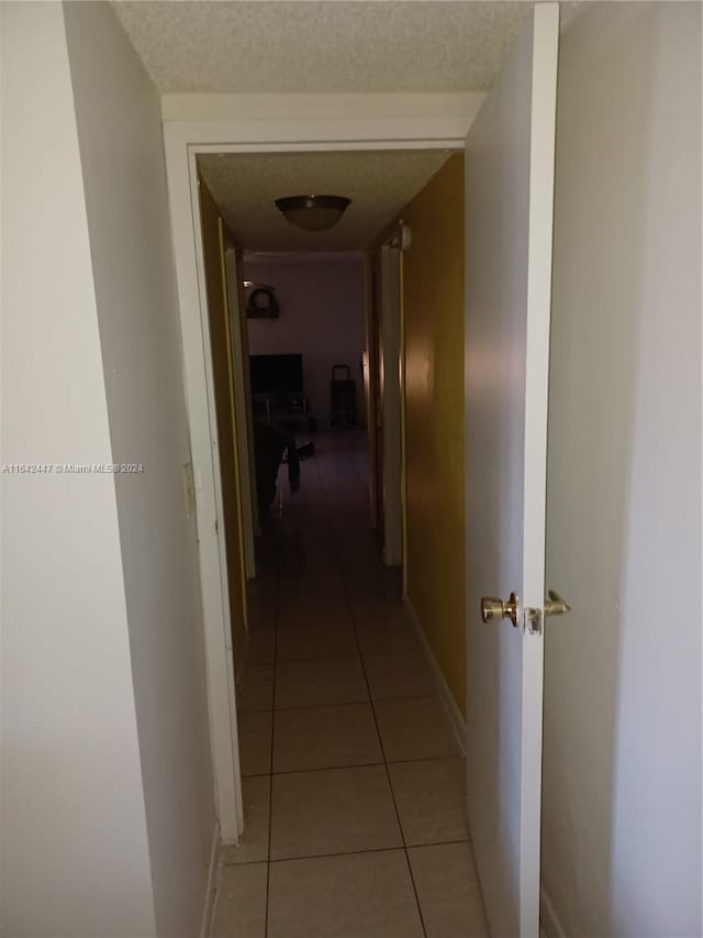 corridor featuring tile patterned flooring and a textured ceiling