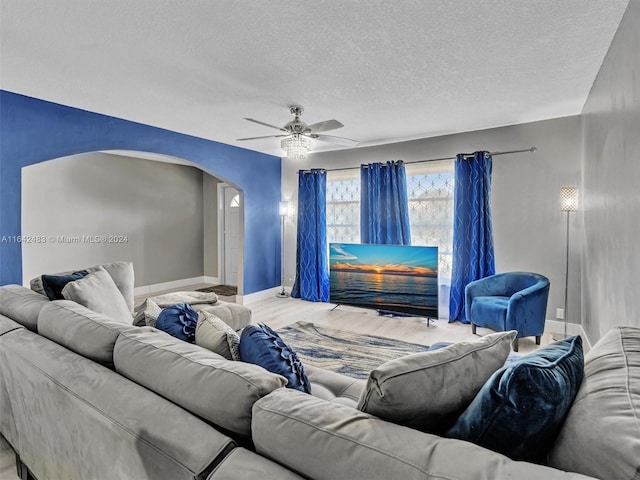 living room featuring ceiling fan and a textured ceiling