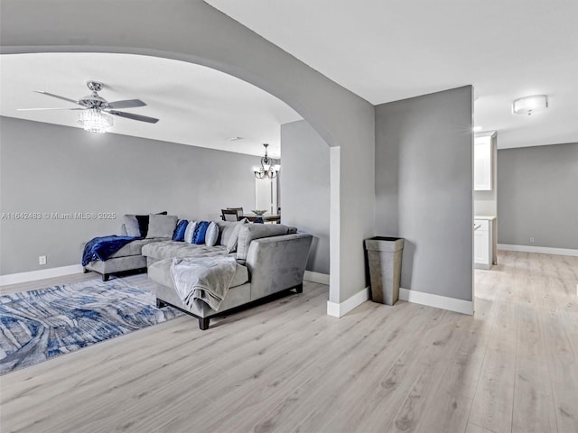 living room with ceiling fan with notable chandelier and light hardwood / wood-style floors