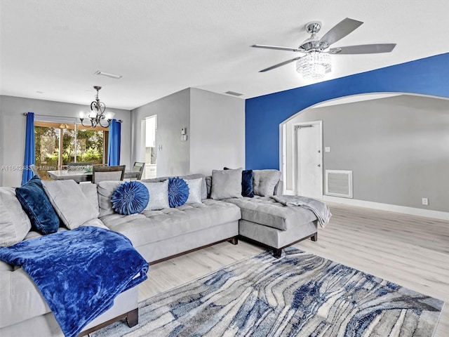 living room featuring ceiling fan with notable chandelier and light wood-type flooring