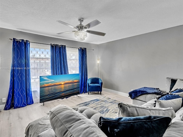 living room featuring ceiling fan, light hardwood / wood-style floors, and a textured ceiling