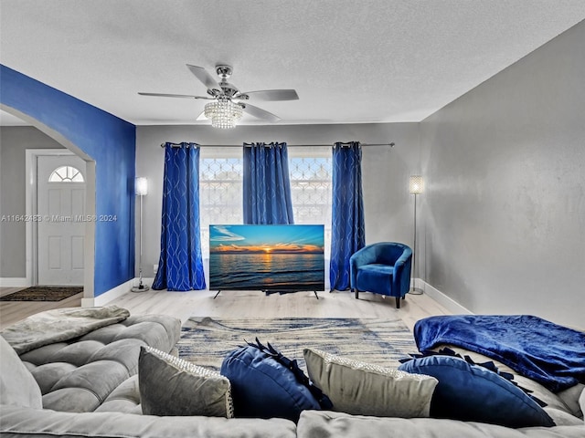 living room featuring a textured ceiling, ceiling fan, and wood-type flooring