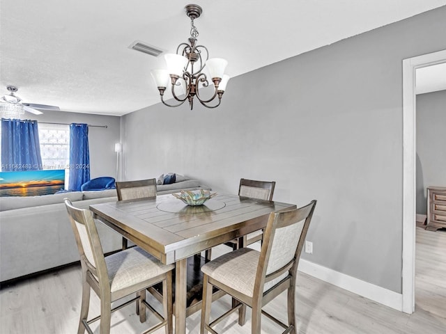 dining area featuring a textured ceiling, light hardwood / wood-style floors, and ceiling fan with notable chandelier